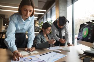 Equipe analisando gráficos e dados em um escritório moderno, exemplificando conceitos de administração empresarial.