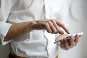 Homem de camisa social branca utilizando o celular da empresa