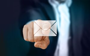Homem vestido com um terno, apontando para a imagem de uma carta, a qual representa um e-mail.