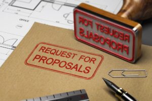 Carimbo e envelope marrons com a inscrição 'Request for Proposals (RFP)' ao lado de caneta tinteiro e clipe.