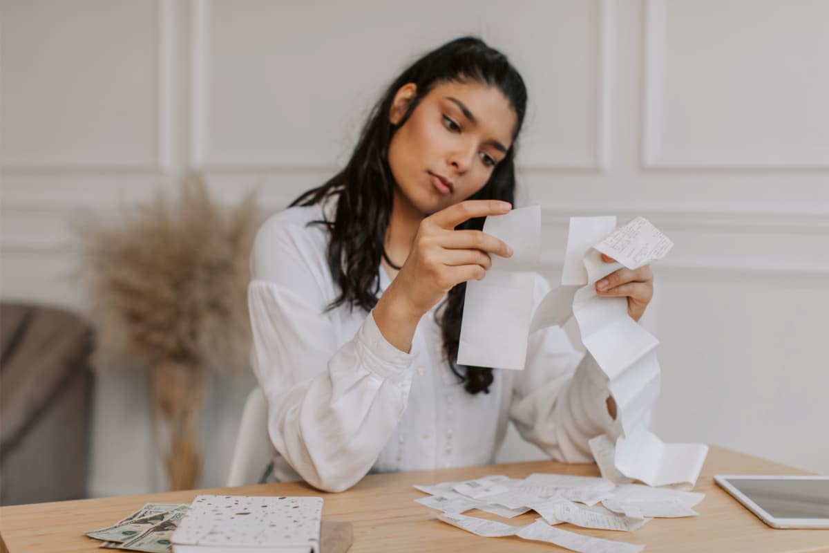 Mulher organizando recibos em uma mesa, demonstrando como a tecnologia RPA pode otimizar o gerenciamento de faturas.